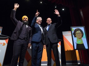 agmeet Singh, from left to right, Charlie Angus and Guy Caron pose for a photograph as Niki Ashton, is seen on a television screen via satellite from Ottawa, before the final federal NDP leadership debate in Vancouver, B.C., on Sunday, September 10, 2017.