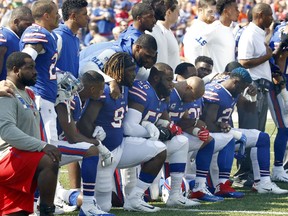 In this Sunday, Sept. 24, 2017, file photo, Buffalo Bills players take a knee during the playing of the national anthem prior to an NFL football game against the Denver Broncos in Orchard Park, N.Y.