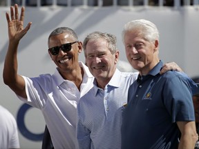 Former U.S. Presidents, from left, Barack Obama, George Bush and Bill Clinton greet spectators on the first tee before the first round of the Presidents Cup at Liberty National Golf Club in Jersey City, N.J., Thursday, Sept. 28, 2017. (AP Photo/Julio Cortez)