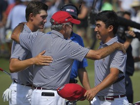 Captain Spider Miller, center, of the United States, embraces Maverick McNealy, left, and Doug Ghim after they completed their round during foursomes at the Walker Cup golf matches at Los Angeles Country Club, Sunday, Sept. 10, 2017, in Los Angeles. (AP Photo/Mark J. Terrill)