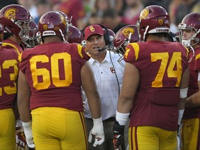 FILE - In this Sept. 16, 2017, file photo, Southern California head coach Clay Helton talks to his team during the first half of an NCAA college football game against Texas in Los Angeles. With a quarter of the college football season in the books, 24 undefeated teams remain, along with the possibility that each Power Five conference could have an undefeated champion. That's way off. For now, a couple of cross-divisional conference games matching ranked teams, No. 2 Clemson at No. 12 Virginia Tech and No. 5 USC at No. 16 Washington State, highlight the schedule and will be part whittling the field of unbeaten teams. (AP Photo/Mark J. Terrill, File)