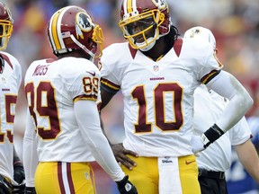 FILE - In this Aug. 25, 2012, file photo, Washington Redskins quarterback Robert Griffin III (10) talks with teammates Santana Moss (89)) during a preseason NFL football game against the Indianapolis Colts in Landover, Md. Moss, during his weekly radio appearance  in Washington, says Griffin took credit for coach Mike Shanahan and offensive coordinator Kyle Shanahan being fired by the Washington Redskins in 2013. (AP Photo/Nick Wass, File)