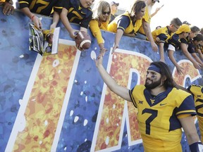 FILE - In this Saturday, Sept. 9, 2017, file photo, West Virginia quarterback Will Grier (7) celebrates their victory with fans at the conclusion of an NCAA college football game against East Carolina in Morgantown, W.Va.  Two years after a promising football career at Florida came crashing down, Will Grier is now the toast of West Virginia with two strong performances so far in the 2017 season. Yet he's not the most famous person in his family. Younger brothers Hayes and Nash are huge internet stars, building their own brands to millions of teenagers and young adults.(AP Photo/Raymond Thompson, File)