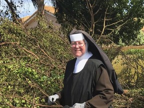 In this Tuesday, Sept. 12, 2017, photo provided by the Miami-Dade Police Department, Sister Margaret Ann holds a chain saw near Miami, Fla. Police said the nun was cutting trees to clear the roadways around Archbishop Coleman Carrol High School in the aftermath of Hurricane Irma. (Miami-Dade Police Department via AP)