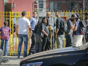 Parents and guardians arriving for after school pickup are blocked at an entry at Urban Assembly School for Wildlife Conservation, Wednesday Sept. 27, 2017, in New York. Earlier, a high school student fighting with two classmates at the school pulled a switchblade killing one boy and wounding another. (AP Photo/Bebeto Matthews)