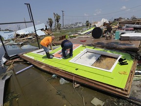 FILE - In this Saturday, Sept. 2, 2017, file photo, people work to remove a door from what had been an interior wall of a business, in Rockport, Texas, in the aftermath of Harvey. Small businesses with customers or suppliers along the Gulf Coast and in Florida are feeling the financial impact from Hurricanes Harvey and Irma. Sales have dropped off as people and businesses prepared for the hurricanes, and are still down as everyone assesses and deals with the devastation left by the storms. Many companies located far away have to strategize to boost their sales and in some cases, find alternative vendors. (AP Photo/Eric Gay)
