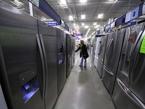 FILE - In this Thursday, Jan. 16, 2014, file photo, a woman walks through a display of refrigerators at a Lowe's store in Cranberry Township, Pa. Buying a major appliance can be intimidating, but it doesn't have to be hard. To find one that both you and your bank account are happy with, do your homework, visit a store and ask for a deal. And don't buy an extra warranty without reading the fine print. (AP Photo/Gene J. Puskar, File)