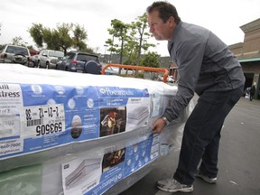 FILE - In this Feb. 27, 2012, file photo, Chris Kraft loads a new mattress set that he purchased at Costco Wholesale store in Glendale, Calif. Shopping for a new mattress has never been easier, or more complicated. The variety of mattress options can be confusing even before you try to sift through the jargon soup of components and materials touted by manufacturers as the leading edge of comfort.  (AP Photo/Damian Dovarganes, File)