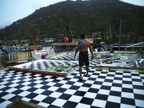 FILE - In this Tuesday, Sept. 26, 2017, file photo, Nestor Serrano walks on the upstairs floor of his home, where the walls were blown off, in the aftermath of Hurricane Maria, in Yabucoa, Puerto Rico. Maria has thrown Puerto Rico's already messy economic recovery plans into disarray. (AP Photo/Gerald Herbert, File)