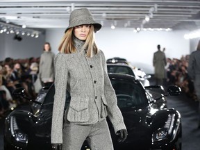 A model poses in front of Ralph Lauren's car collection in The Garage, at the Ralph Lauren fashion show during Fashion Week, Tuesday, Sept. 12, 2017, in Bedford, N.Y. (AP Photo/Kathy Willens)