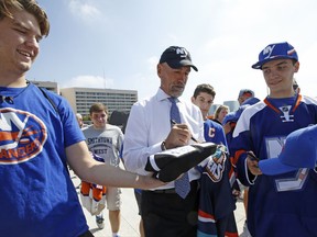 Fans seeking autographs clamor around retired NHL hockey player Bob Nystrom, center, before a preseason NHL hockey game between the New York Islanders and the Philadelphia Flyers in Uniondale, N.Y., Sunday, Sept. 17, 2017. Nystrom is a retired Swedish-born, Canadian professional ice hockey right winger who played for the New York Islanders from 1972–86. (AP Photo/Kathy Willens)