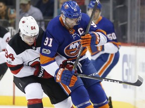 New Jersey Devils center Joseph Blandisi (64) and New York Islanders center John Tavares (91) go for a puck over Tavares's laces during the first period of a preseason NHL hockey game in New York, NY, Monday, Sept. 25, 2017. (AP Photo/Kathy Willens)