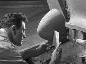 This 1954 photo Courtesy of General Motors shows a Buick Design Studio creative clay sculptor as he molds the clay on a model GM automobile. (Courtesy of General Motors via AP)