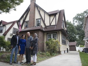 In this Saturday, Sept. 16, 2017 photo, Abdi Iftin, left, of Somalia, Uyen Nguyen, second from left, of Vietnam, Eiman Ali, right, of Somalia born in Yemen, and Ghassan al-Chahada, of Syria pose for a photo outside President Donald Trump's boyhood home in the Jamaica Estates neighborhood of the Queens borough of New York. The house that Trump's father built is now a rental available on Airbnb. The international anti-poverty organization Oxfam rented it Saturday and invited refugees to share their stories with journalists. (AP Photo/Mary Altaffer)