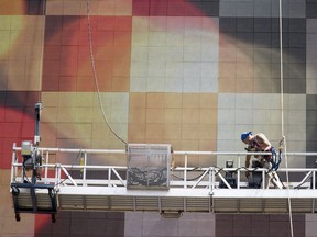 In this Thursday, July 20, 2017, photo, a worker on a suspended scaffold works on the electronic Coca Cola billboard in New York's Times Square. On Thursday, Sept. 7, 2017, the Labor Department issues revised data on productivity in the second quarter. (AP Photo/Mary Altaffer)