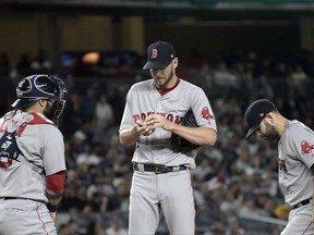 Boston Red Sox pitcher Chris Sale, catcher Sandy Leon, left, and second baseman Dustin Pedroia, right, gather on the mound during the fourth inning of a baseball game against the New York Yankees Sunday, Sept.3, 2017, at Yankee Stadium in New York. (AP Photo/Bill Kostroun)