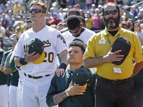 Oakland Athletics' Mark Canha (20) places his hand on the shoulder of Bruce Maxwell as Maxwell takes a knee during the national anthem prior to a baseball game against the Texas Rangers, Sunday, Sept. 24, 2017, in Oakland, Calif. (AP Photo/Ben Margot)