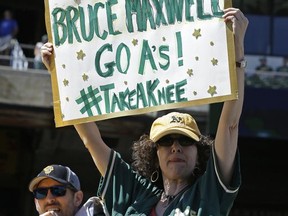 Nancy Levine of Marin, Calif., holds a sign in support of Oakland Athletics' Bruce Maxwell, who knelt during the national anthem for a second day prior to the baseball game against the Texas Rangers Sunday, Sept. 24, 2017, in Oakland, Calif. (AP Photo/Ben Margot)