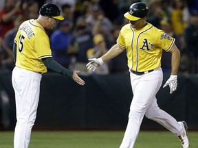 Oakland Athletics' Matt Olson, right, celebrates with third base coach Steve Scarsone after hitting a home run off Los Angeles Angels' Blake Wood during the fifth inning of a baseball game Tuesday, Sept. 5, 2017, in Oakland, Calif. (AP Photo/Ben Margot)