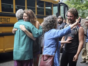 Families reunite after campers were evacuated from a forest fire in the Eagle Creek area of the Columbia River Gorge Sunday, Sept. 3, 2017. Two busloads of hikers in Oregon were reunited with their friends and family Sunday morning after they were forced to spend the night in the mountains east of Portland when a wildfire closed their trail and they were trapped between two blazes. (Mark Graves/The Oregonian via AP)
