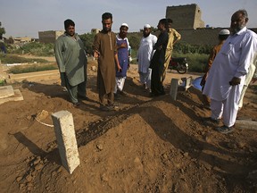 People look at the graves of alleged victims of two so-called honor killings, in Karachi, Pakistan, Wednesday, Sept. 13, 2017.