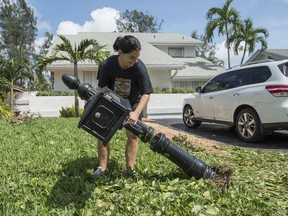 Audrey Foy, originally from Laval, Que., picks up the mailbox on her front lawn following the passing of Hurricane Irma, Monday, September 11, 2017 in Davie, Fla. THE CANADIAN PRESS/Paul Chiasson