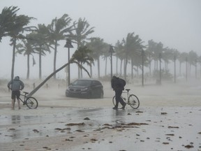 Two guys walks their bicycle along a flooded street on the waterfront of Fort Lauderdale, Fla., as Hurricane Irma passes through on Sunday, September 10, 2017. THE CANADIAN PRESS/Paul Chiasson