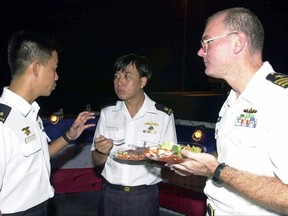 FILE - This July 4, 2001, file photo provided by the U.S. Department of Defense shows U.S. Navy Commander Dave Kapaun, right, with Republic of Singapore Navy Major Danny Tan, left, and Republic of Singapore Major H .C. Lim at a reception on board the U.S. Navy dock landing ship USS Rushmore during the seventh annual Cooperation Afloat Readiness and Training (CARAT) Exercise. Retired U.S. Navy Commander Kapaun,who pleaded guilty to lying about his relationship with a Malaysian defense contractor nicknamed "Fat Leonard" is facing sentencing. (Kevin H. Tierney/U.S. Department of Defense via AP, file)