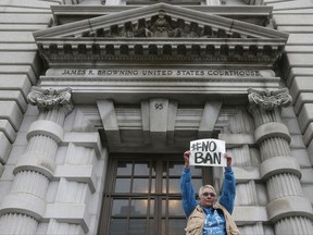 FILE- In this Feb. 7, 2017, file photo, Karen Shore holds up a sign outside of the 9th U.S. Circuit Court of Appeals in San Francisco. The appeals court on Thursday, Sept. 7, rejected the Trump administration's limited view of who is allowed into the United States under the president's travel ban, saying grandparents, cousins and similarly close relations of people in the U.S. should not be prevented from coming to the country. (AP Photo/Jeff Chiu, File)