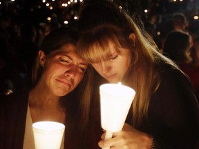 FILE- In this Oct. 1, 2015, file photo, Kristen Sterner, left, and Carrissa Welding, both students at Umpqua Community College, embrace each other during a candlelight vigil for those killed during a shooting at the college in Roseburg, Ore. Oregon authorities have released a detailed report on the 2015 shooting that left nine people dead and nine injured. The report released Friday, Sept. 8, 2017,  includes a six-page, typewritten 'manifesto' that the suspect, Christopher Harper-Mercer, left on a thumb drive for police to find. (AP Photo/Rich Pedroncelli, file)