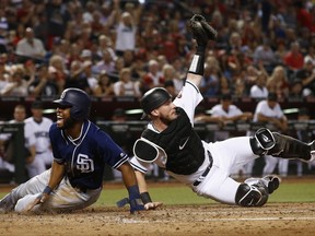 Arizona Diamondbacks' Chris Herrmann, right, shows the umpire the ball in his glove after tagging out San Diego Padres' Manuel Margot, left, as Margot tried to score during the third inning of a baseball game Friday, Sept. 8, 2017, in Phoenix. (AP Photo/Ross D. Franklin)