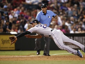 Colorado Rockies' Nolan Arenado dives for a grounder hit by Arizona Diamondbacks' A.J. Pollock before making the play and throwing to first base for the out during the sixth inning of a baseball game, Monday, Sept. 11, 2017, in Phoenix. (AP Photo/Ross D. Franklin)