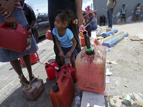 Abi de la Paz de la Cruz, 3, holds a gas can as she waits in line with her family, to get fuel from a gas station, in the aftermath of Hurricane Maria, in San Juan, Puerto Rico, Monday, Sept. 25, 2017. The U.S. ramped up its response Monday to the humanitarian crisis in Puerto Rico while the Trump administration sought to blunt criticism that its response to Hurricane Maria has fallen short of it efforts in Texas and Florida after the recent hurricanes there. (AP Photo/Gerald Herbert)