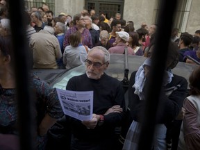 A man stands in the street reading a pamphlet urging people to vote during an event to support the Catalonia independence referendum in Madrid, Spain, Sunday, Sept. 17, 2017. Political tensions in Spain are increasing as the proposed voting date of Oct. 1 nears. The Catalan government has been scrambling to push forward the vote, despite the central government's warnings that local municipalities are not allowed to use public buildings for it and mayors can be legally prosecuted for it. (AP Photo/Paul White)