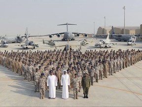 In this Monday, Sept. 11, 2017 photo released by Qatar News Agency, QNA, the Qatari Emir Sheikh Tamim bin Hamad Al Thani, centre front, poses for a photo with Emiri Air Force at al-Udeid Air Base in Doha, Qatar. Sheikh Tamim bin Hamad Al Thani's visit to al-Udeid Air Base throws into sharp relief the delicate balancing act the U.S. faces in addressing the Qatar crisis. (QNA via AP)