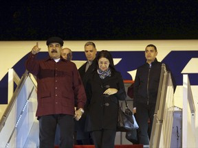 Venezuela's President Nicolas Maduro gestures as he walks down the gangway with his wife, Cilia Flores, upon his arrival at Houari-Boumediene airport near the Algerian capital, Algiers, Monday, Sept. 11, 2017. (AP Photo/Sidali Djarboub)