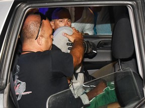 Italian police escort a teenager, at center with his head covered, in the police headquarters in Rimini, Italy Saturday Sept. 2, 2017. Two Moroccan teenagers suspected of being among four males who gang raped a Polish tourist and beat her companion unconscious on an Italian resort beach were identified at a police station Saturday by a Peruvian woman who reported being raped by the same gang shortly after the first attack, Italian media reported. (Manuel Migliorini/ANSA via AP)