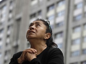 A woman prays during an outdoor Mass service, held outside Saint James Apostle Parish, because the church building suffered some damage during the 7.1-magnitude earthquake, in the Plaza de las Tres Culturas in Tlatelolco, Mexico City, Sunday, Sept. 24, 2017. As the search continued Sunday for survivors and the bodies of people who died in quake-collapsed buildings, specialists have fanned out to inspect buildings and determine which are unsafe after Tuesday's powerful earthquake. (AP Photo/Rebecca Blackwell)