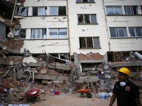 A rescue worker walks in front of an apartment building whose first four floors collapsed, in the Lindavista neighborhood of Mexico City, Wednesday, Sept. 20, 2017. People by the millions rushed from homes and offices across central Mexico, after a 7.1 earthquake, sometimes watching as buildings they had just fled fell behind them with an eruption of dust and debris. (AP Photo/Rebecca Blackwell)