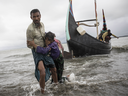 A Rohingya man carries an elderly woman, after the wooden boat they were travelling on from Myanmar crashed into the shore and tipped everyone out on Sept. 12, 2017 in Dakhinpara, Bangladesh.