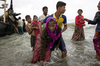 A young Rohingya man carries an elderly woman, after the wooden boat they were travelling on from Myanmar crashed into the shore and tipped everyone out on Sept. 12, 2017 in Dakhinpara, Bangladesh.