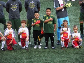 Five-year-old Derrick Tellez and his older brother Josue Tellez, right, take part in the national anthem on field with the Portland Timbers before a soccer match against Orlando City on Sunday, Sept. 24, 2017, in Portland, Ore. Derrick Tellez, a goalkeeper, was signed to a one-game contract with the Timbers as part of his wish with Make-A-Wish Oregon. (AP Photo/Anne M. Peterson)