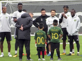 Five-year-old Derrick Tellez (00) and his older brother Josue (10) are introduced to the Portland Timbers by coach Caleb Porter on Friday, Sept. 22, 2017, at the Timbers' practice facility in Beaverton, Ore. Tellez, who has had three surgeries for a cancerous brain tumor, was signed to a one-game contract with the MLS soccer team, granting his wish with Make-A-Wish Foundation Oregon. (AP Photo/Anne M. Peterson)