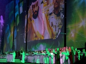 In this Saturday, Sept. 23, 2017 photo released by Saudi Press Agency, SPA, Saudi men perform under a giant screen showing an image of Saudi Crown Prince Mohammed Bin Salman during National Day ceremonies, at the King Fahd Stadium in Riyadh, Saudi Arabia. Saudi Arabia is celebrating its National Day with an array of family-friendly festivities, including allowing women to enter the main stadium in the capital, Riyadh, for the first time, to see a performance recounting the country's founding 87 years ago. The King Fahd stadium has previously been reserved for male-only crowds to watch soccer matches. (Saudi Press Agency via AP)