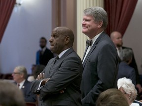 FILE - In this Sept. 12, 2017, file photo State Sen. Steven Bradford, D-Gardena, left, and Assemblyman Mark Stone, D-Scotts Valley, watch as the votes are posted for Stone's youth parole measure before the Senate, in Sacramento, Calif. The legislature approved the bill, AB1308, and if signed by the governor, would allow inmates who are under the age of 25, and who have served at least 15 years of their sentenced to be considered for parole. (AP Photo/Rich Pedroncelli, File)