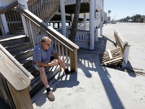 Peter Rapnikas, owner of Finn's Island Grill, sits dejected on the steps to his restaurant while Palmetto Blvd is covered in several feet of sand after Tropical Storm Irma hit Edisto Beach, S.C., Tuesday, Sept. 12, 2017. Edisto Beach suffered the same fate last year with Hurricane Matthew and shut Rapnikas down for several months. "Unbelievable. I don't know if I'm going to re-open" Rapnikas said. (AP Photo/Mic Smith)