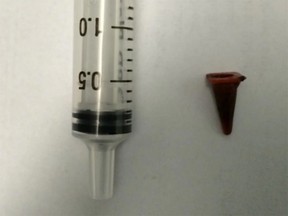 The toy traffic cone compared next to a 2.5 mL syringe to illustrate size.