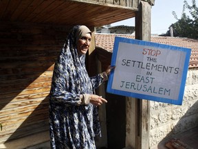 A Palestinian woman holds a sign outside a house in east Jerusalem Tuesday, Sept. 5, 2017. Israeli officials have evicted a Palestinian family from their home in east Jerusalem to make way for new Jewish tenants. (AP Photo/Mahmoud Illean)