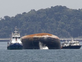 The bow of a partially submerged, capsized dredger is seen in the west part of the Singapore Strait, Thursday, Sept. 14, 2017, in Singapore. An oil tanker and a dredger collided in Singapore waters Wednesday, capsizing the dredger and leaving two dead and three missing, authorities said. (AP Photo/Wong Maye-E)