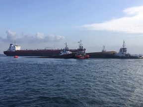 This photo provided by the Maritime and Port Authority of Singapore, four tug boats moving the partially submerged dredger safely to an area near Pulau Senang, Singapore, for follow up underwater search operations, Wednesday, Sept. 13, 2017.  An oil tanker and a dredger collided in Singapore waters Wednesday, capsizing the dredger and leaving five of its crew missing, authorities said.  The dredger was left partially submerged and an underwater search and rescue operation was underway on the vessel, the Maritime and Port Authority of Singapore said.  (The Maritime and Port Authority of Singapore via AP)